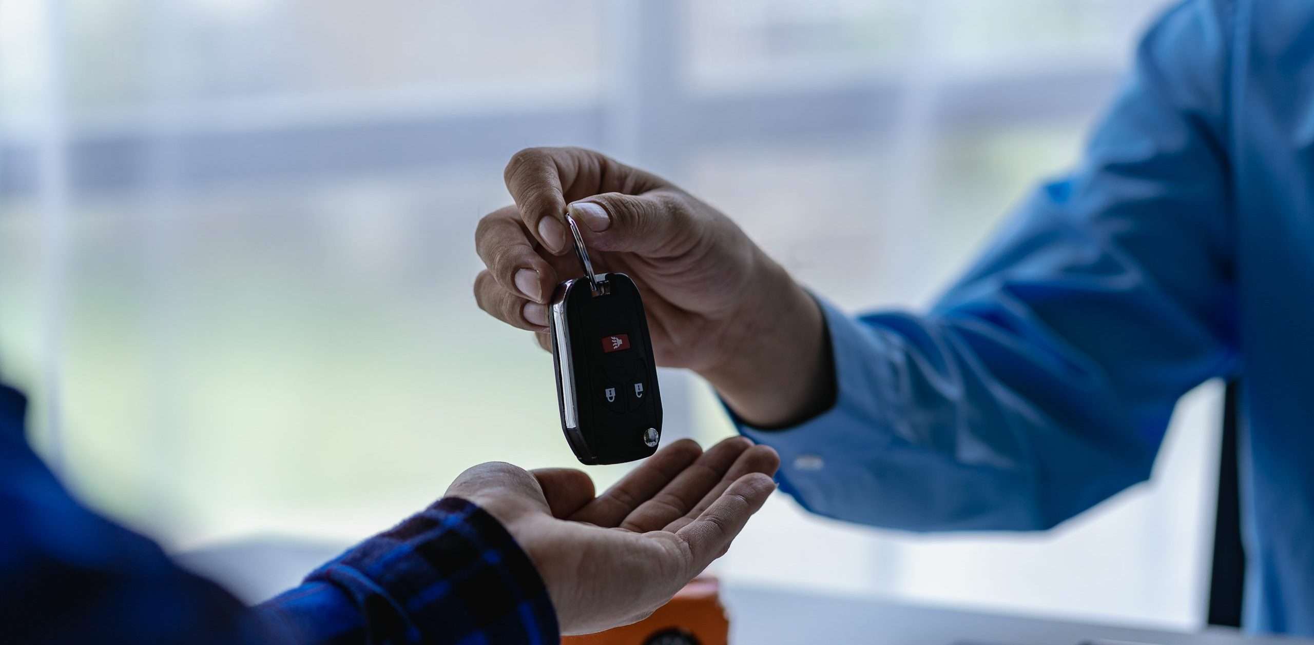 Young salesman holding car keys in hands of car rental business customer sell or buy services Asian male sales representative sells important cars to client tenants.